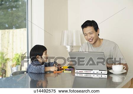 Father and son sitting at kitchen table, Father working on computer View Large Photo Image Stock Photography - Father and son sitting at kitchen table, Father working on computer. Fotosearch