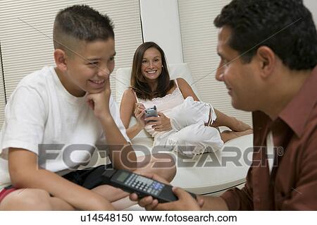 Stock Image - Father Showing Son Remote Control in living room, close up. Fotosearch