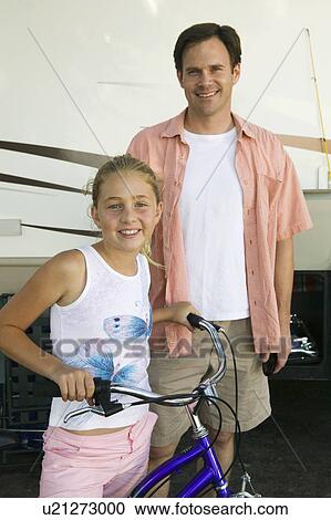 Stock Image - Father with Daughter on Bike Next to RV. Fotosearch