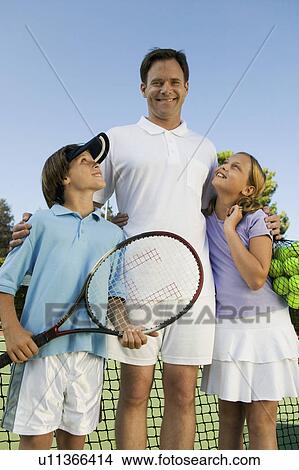 Father with Son and Daughter by net on Tennis Court, portrait, front view View Large Photo Image Picture - Father with Son and Daughter by net on Tennis Court, portrait, front view. Fotosearch