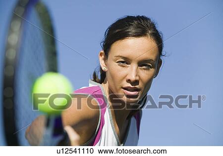 Stock Image - Female Tennis Player Hitting Ball, close up of racket, focus on player. Fotosearch