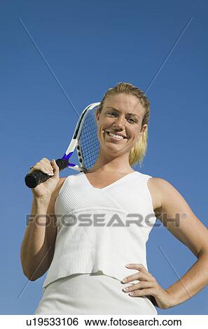 Stock Photograph - Female tennis player Holding Tennis Racket, portrait, low angle view. Fotosearch