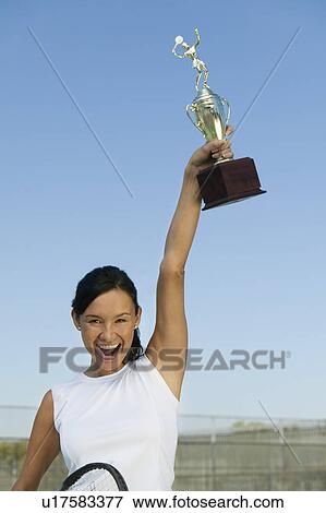 Female tennis player on tennis court holding up trophy, portrait View Large Photo Image Stock Photo - Female tennis player on tennis court holding up trophy, portrait. Fotosearch