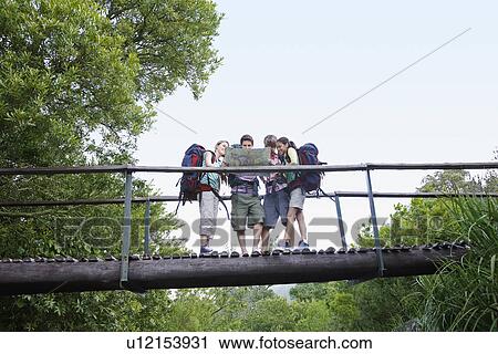 Four teenagers (16-17 years) backpacking in forest, reading map on bridge View Large Photo Image Stock Image - Four teenagers (16-17 years) backpacking in forest, reading map on bridge. Fotosearch