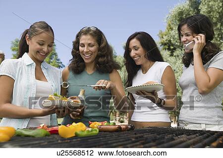 Stock Image - Four women around outdoor grill.. Fotosearch