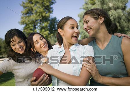 Four women in park, one woman holding football. View Large Photo Image Stock Image - Four women in park, one woman holding football.. Fotosearch