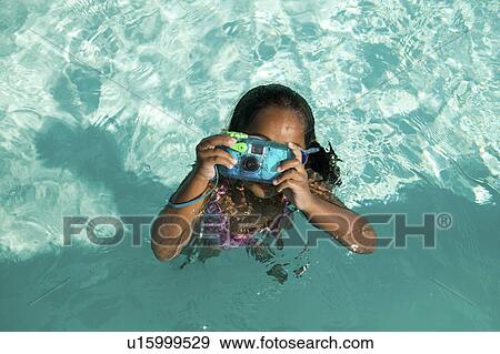 Girl (5-6) Using Waterproof Camera in Swimming Pool, overhead view. View Large Photo Image Stock Photo - Girl (5-6) Using Waterproof Camera in Swimming Pool, overhead view.. Fotosearch