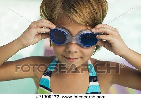 Stock Photo - Girl (7-9) adjusting goggles, smiling.. Fotosearch
