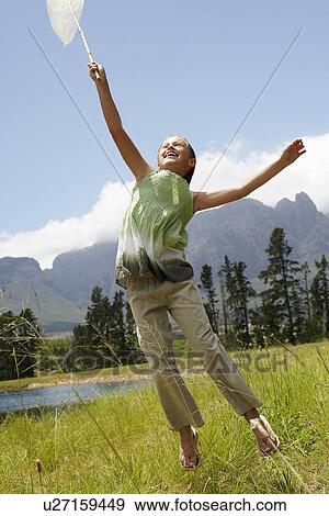 Girl (7-9) in field, reaching towards sky with butterfly net. View Large Photo Image Stock Photo - Girl (7-9) in field, reaching towards sky with butterfly net.. Fotosearch