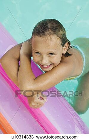 Stock Image - Girl (7-9) in swimming pool, view from above, portrait.. Fotosearch
