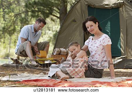 Girl (7-9) sitting at campsite with parents. View Large Photo Image Stock Image - Girl (7-9) sitting at campsite with parents.. Fotosearch