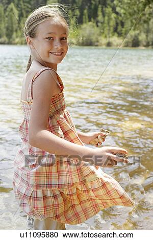 Girl (7-9) standing by lake, holding stones, portrait. View Large Photo Image Stock Image - Girl (7-9) standing by lake, holding stones, portrait.. Fotosearch