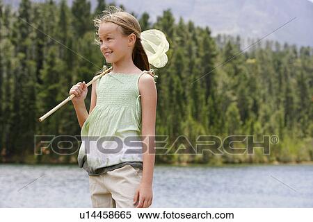 Girl (7-9) standing by lake, holding butterfly net. View Large Photo Image Stock Photography - Girl (7-9) standing by lake, holding butterfly net.. Fotosearch