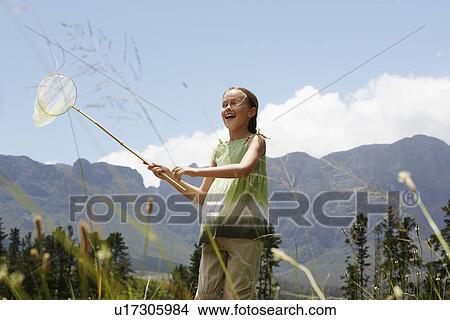 Girl (7-9) standing in field, holding butterfly net, low angle view. View Large Photo Image Picture - Girl (7-9) standing in field, holding butterfly net, low angle view.. Fotosearch