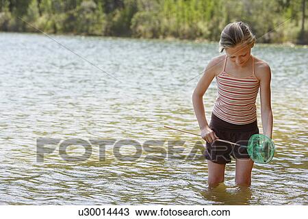 Girl (7-9) standing knee-deep in lake, holding fishing net. View Large Photo Image Stock Image - Girl (7-9) standing knee-deep in lake, holding fishing net.. Fotosearch