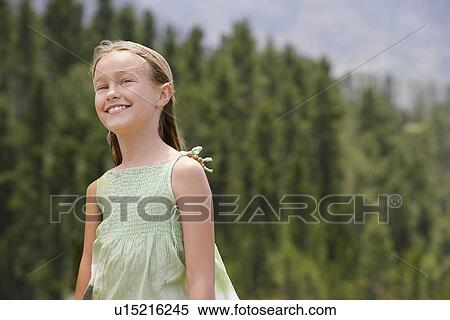 Stock Photography - Girl (7-9) with forest in background, smiling.. Fotosearch