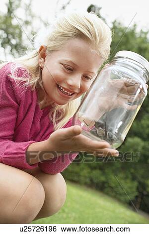 Stock Photograph - Girl Looking at Grasshopper in Jar. Fotosearch