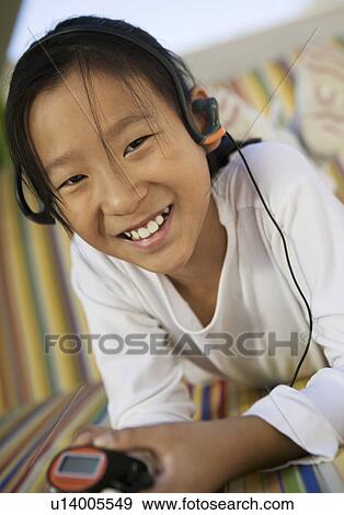 Girl sitting on sofa Listening to MP3 Player, portrait View Large Photo Image Stock Photo - Girl sitting on sofa Listening to MP3 Player, portrait. Fotosearch