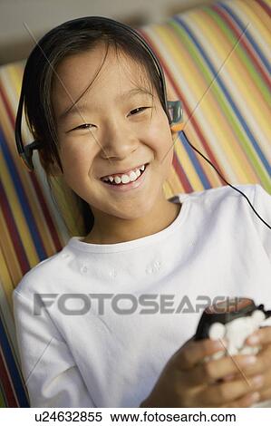 Stock Photography - Girl sitting on sofa Listening to MP3 Player, portrait. Fotosearch