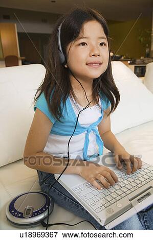 Girl sitting on sofa Using Laptop and Listening to Music View Large Photo Image Stock Photo - Girl sitting on sofa Using Laptop and Listening to Music. Fotosearch