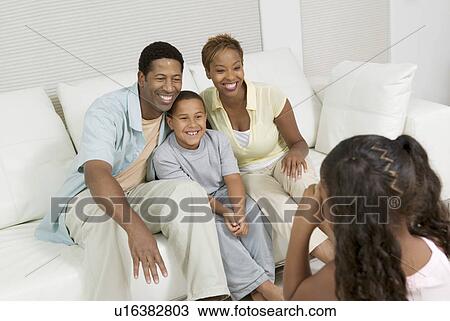 Girl Taking Picture of Family on sofa in living room View Large Photo Image Stock Image - Girl Taking Picture of Family on sofa in living room. Fotosearch