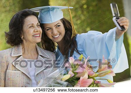 Stock Photograph - Graduate and Grandmother Taking Picture with Cell Phone outside. Fotosearch