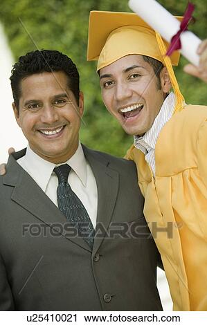 Stock Image - Graduate hoisting diploma with arm around father outside, portrait. Fotosearch