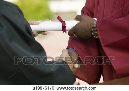 Stock Image - Graduate Receiving Diploma and Handshake, mid section. Fotosearch