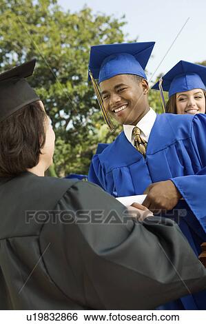 Graduate shaking hand of dean outside, low angle view View Large Photo Image Stock Photograph - Graduate shaking hand of dean outside, low angle view. Fotosearch