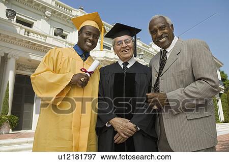 Stock Photo - Graduate with dean and father outside university, low angle view, portrait. Fotosearch