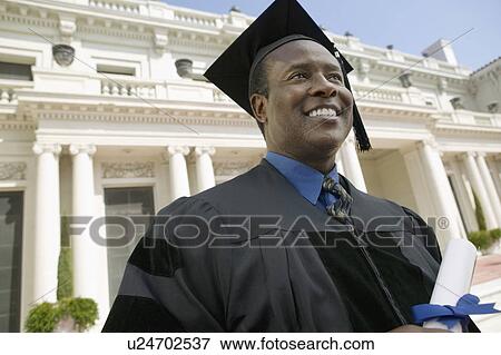 Stock Photo - Graduate with Diploma outside university, low angle view. Fotosearch