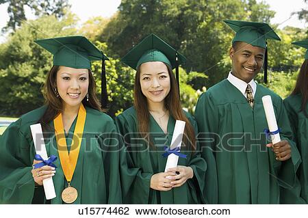 Stock Image - Graduates hoisting diplomas outside university, portrait. Fotosearch