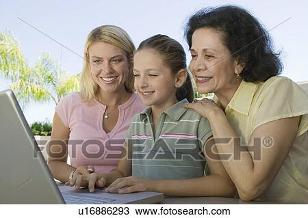 Stock Image - Grandmother and Mother Watching Girl Using Laptop. Fotosearch