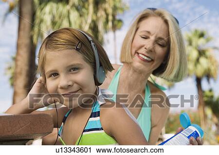 Grandmother applying sunscreen to girl (7-9) listening to headphones, portrait. View Large Photo Image Stock Image - Grandmother applying sunscreen to girl (7-9) listening to headphones, portrait.. Fotosearch