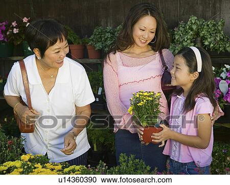 Stock Image - Grandmother, mother and daughter Shopping for Plants in nursery. Fotosearch