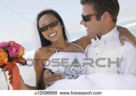 Stock Photo - Groom carrying bride outdoors, (close-up). Fotosearch