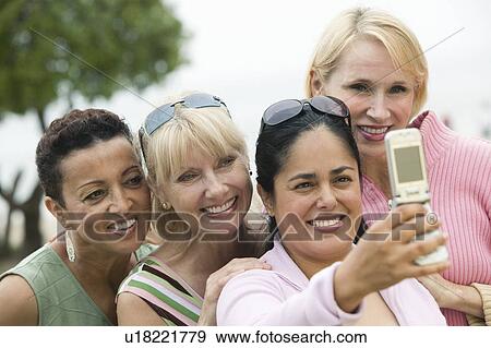 Stock Photo - Group of middle-aged women photographing themselves with a mobile phone. Fotosearch