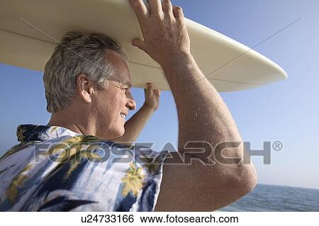 Male surfer carrying surfboard at ocean View Large Photo Image Stock Photograph - Male surfer carrying surfboard at ocean. Fotosearch