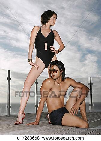 Man and woman in bathing suits on pool deck near ocean View Large Photo Image Stock Photo - Man and woman in bathing suits on pool deck near ocean. Fotosearch