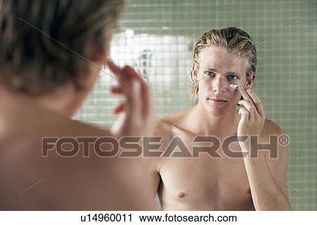 Man applying facial cream in front of mirror View Large Photo Image Stock Image - Man applying facial cream in front of mirror. Fotosearch