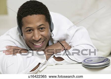 Man lying on sofa Listening to Music on portable CD player, portrait View Large Photo Image Stock Photography - Man lying on sofa Listening to Music on portable CD player, portrait. Fotosearch