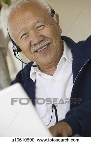Man using headset and laptop, smiling, (portrait) View Large Photo Image Stock Image - Man using headset and laptop, smiling, (portrait). Fotosearch