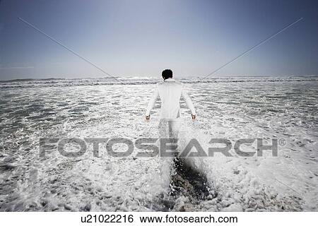 Man walking into sea, being washed by waves, back view View Large Photo Image Stock Photograph - Man walking into sea, being washed by waves, back view. Fotosearch