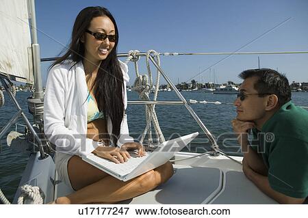 Man with woman using laptop on sailboat View Large Photo Image Stock Photo - Man with woman using laptop on sailboat. Fotosearch