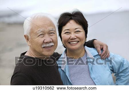 Stock Image - Mature couple smiling, outdoors, (portrait). Fotosearch