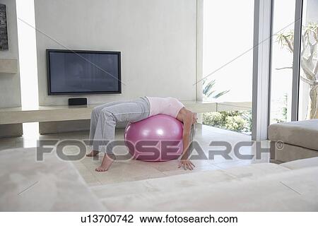 Mature woman stretching, using exercise ball in living room View Large Photo Image Stock Image - Mature woman stretching, using exercise ball in living room. Fotosearch