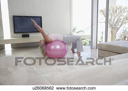Mature woman stretching, using exercise ball in living room View Large Photo Image Stock Image - Mature woman stretching, using exercise ball in living room. Fotosearch