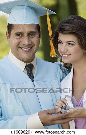 Middle-aged graduate receiving present from daughter outdoors View Large Photo Image Stock Photo - Middle-aged graduate receiving present from daughter outdoors. Fotosearch