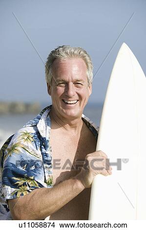 Picture - Middle-aged man holding a surfboard. Fotosearch