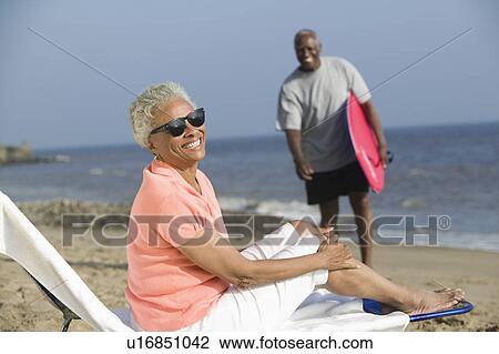 Middle-aged woman sitting on a deckchair on a beach View Large Photo Image Stock Image - Middle-aged woman sitting on a deckchair on a beach. Fotosearch